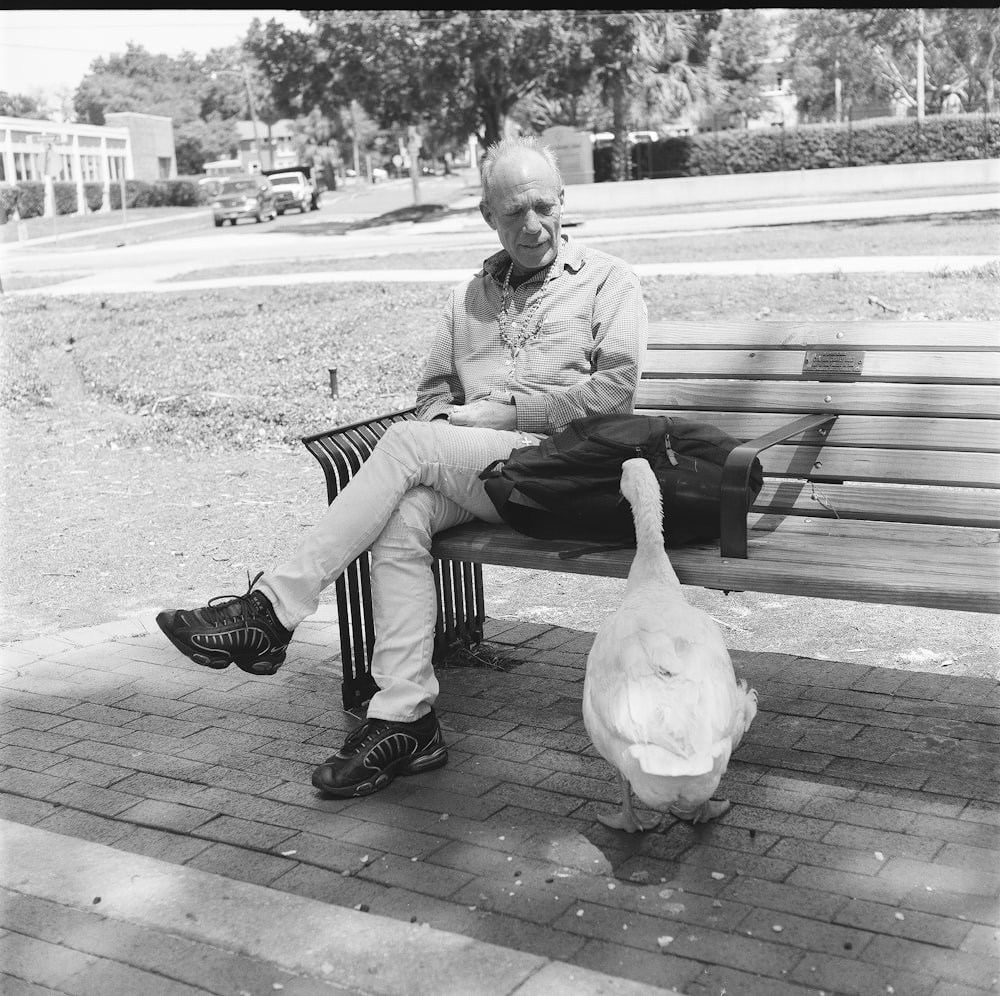 a man sitting on a bench with a pigeon