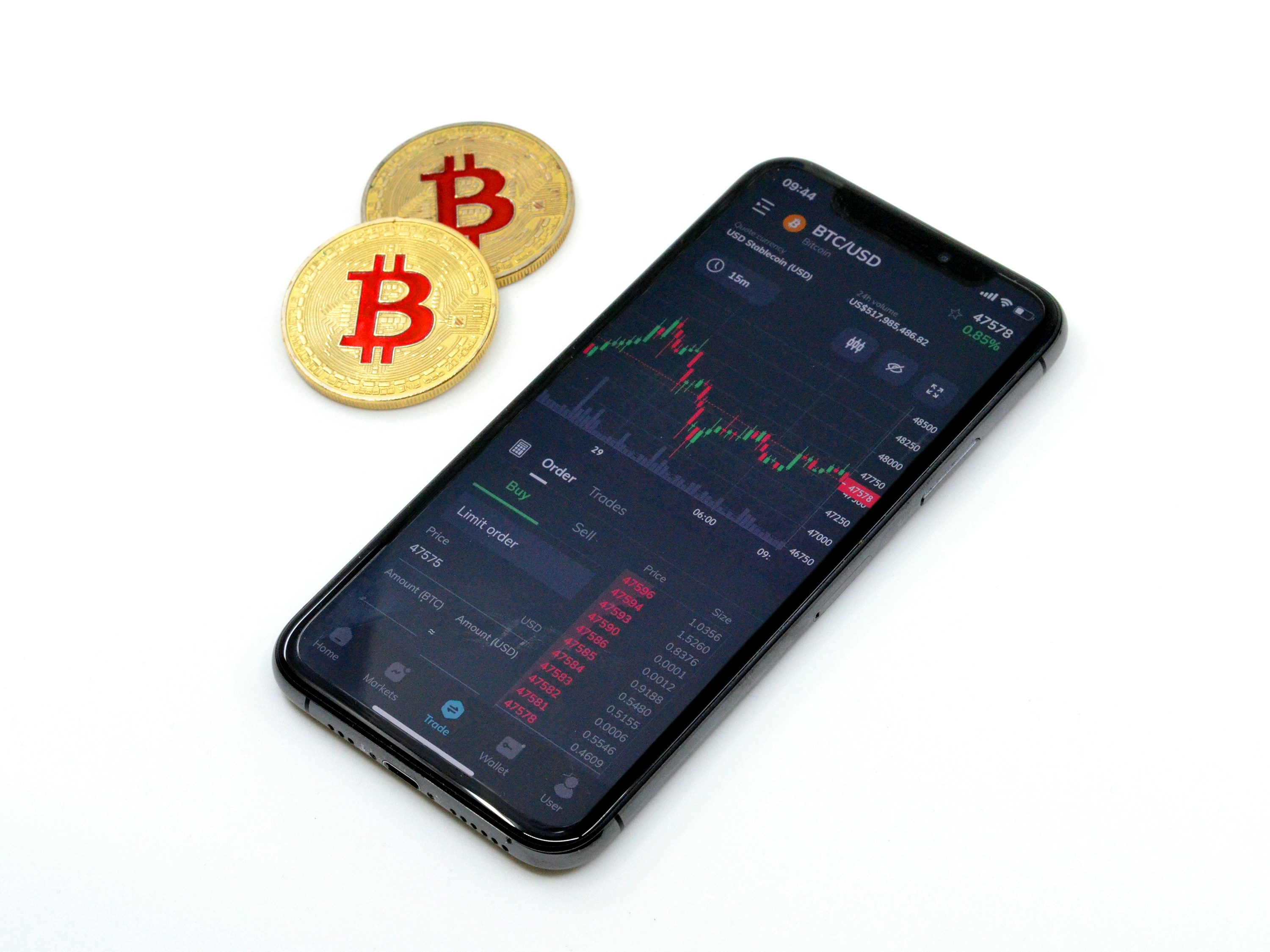 Bitcoin physical coins next to a an Iphone with Trading app on the screen