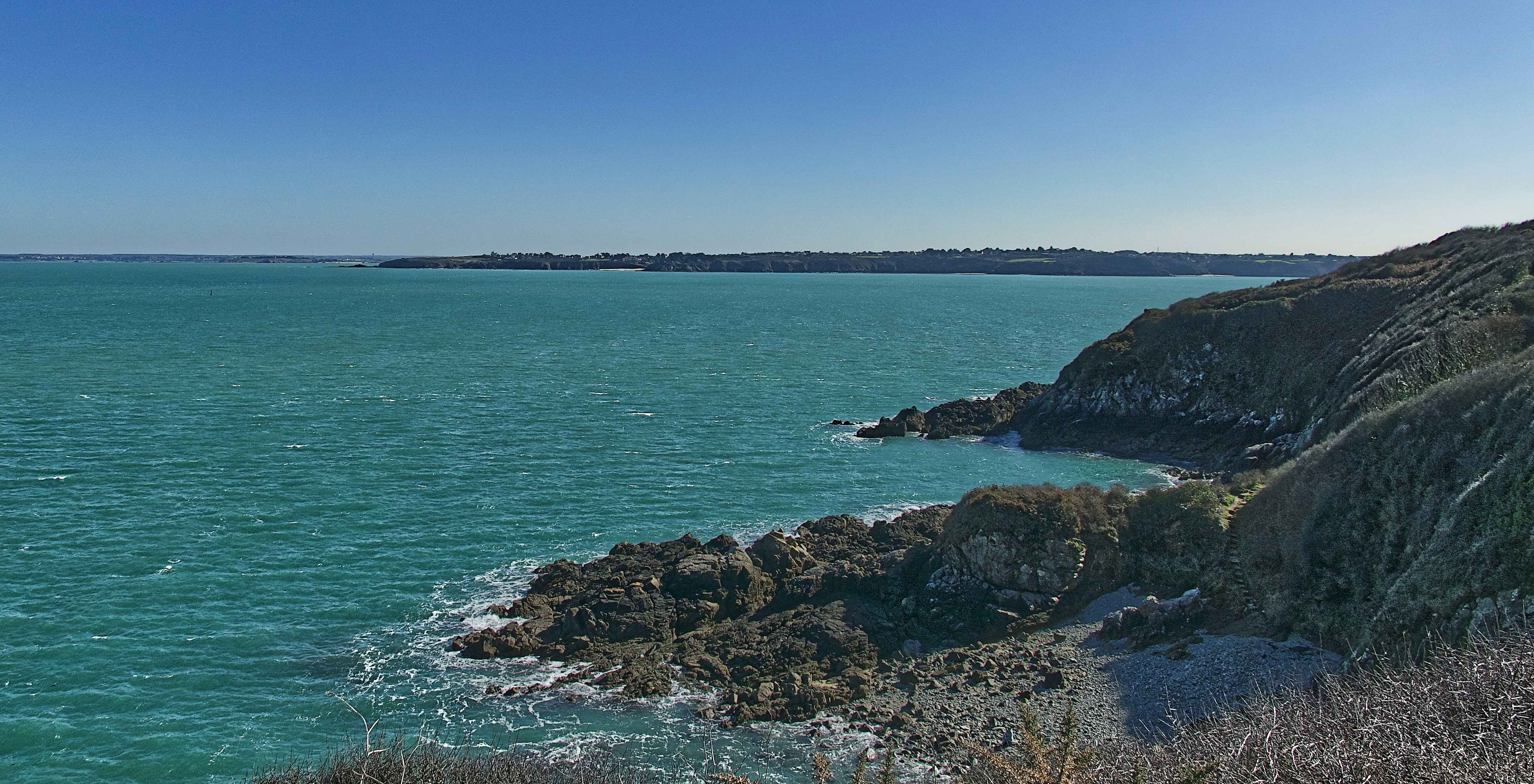 a rocky beach with a body of water in the background
