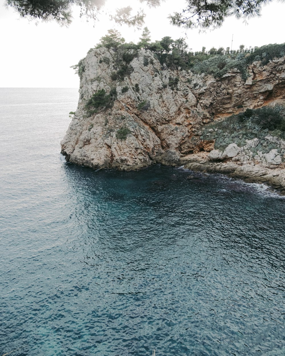 a rocky cliff with a body of water below