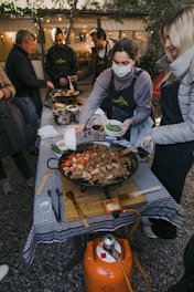 a group of people standing around a table with food on it