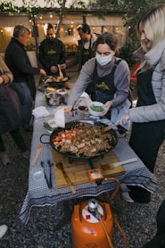 a group of people standing around a table with food on it