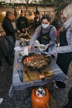 a group of people standing around a table with food on it