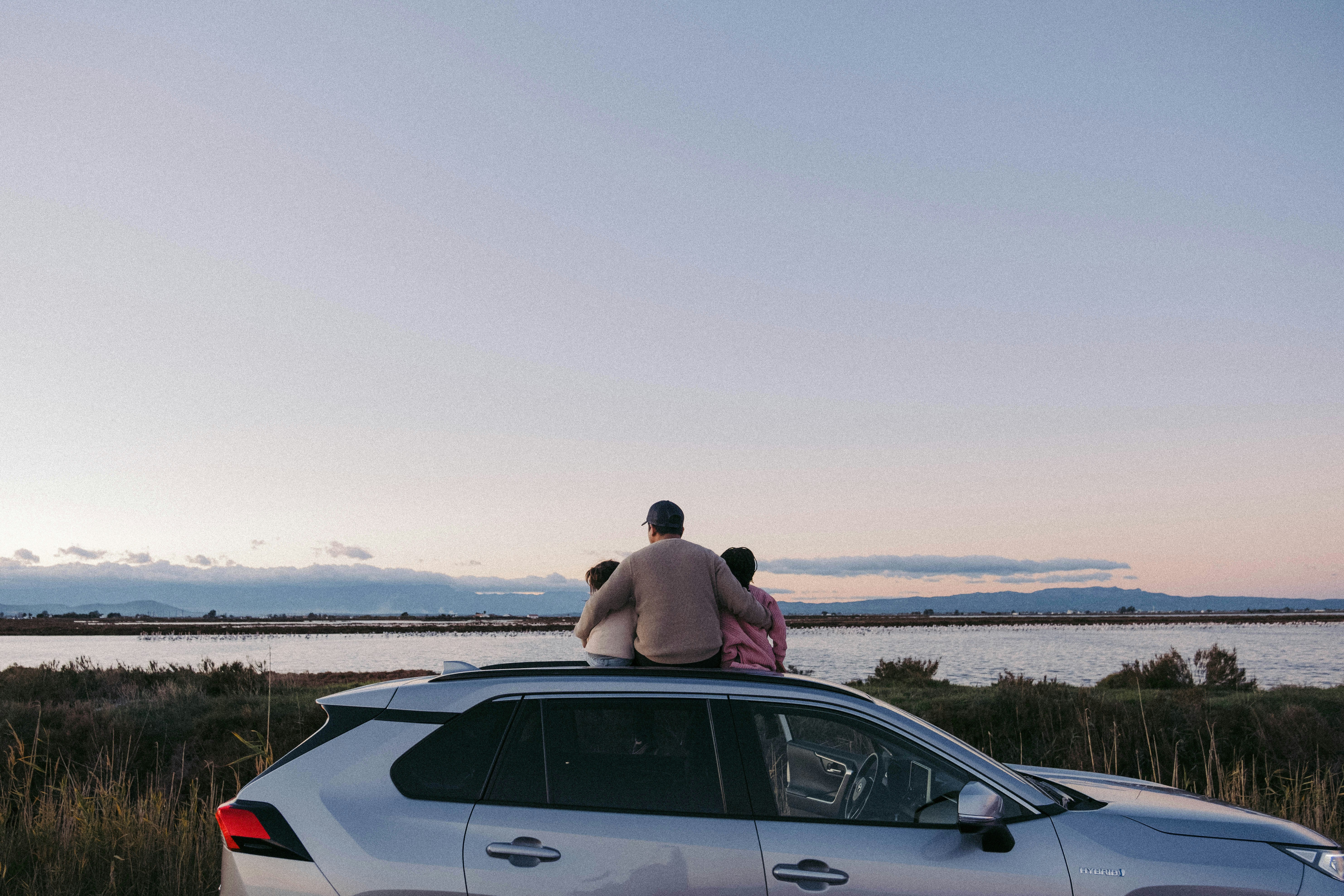 a man and a woman sitting on a car in a field