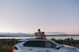 a man and a woman sitting on a car in a field