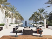a pool with chairs and tables by it and palm trees