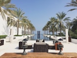 a pool with chairs and tables by it and palm trees