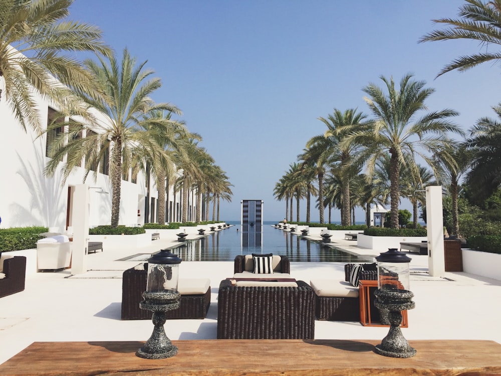 a pool with chairs and tables by it and palm trees