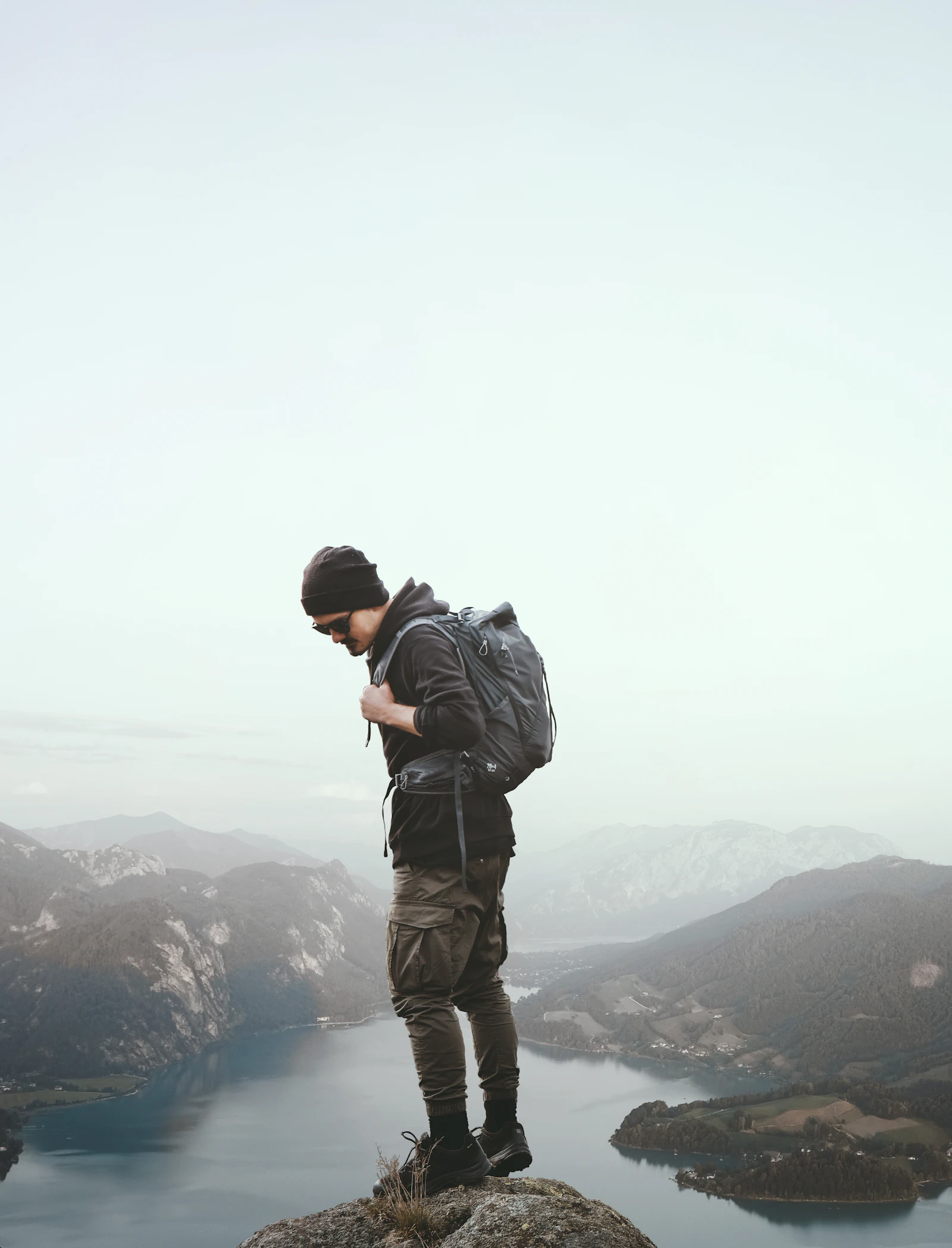 Mature hiker standing atop an Austrian peak above a vast body of water.