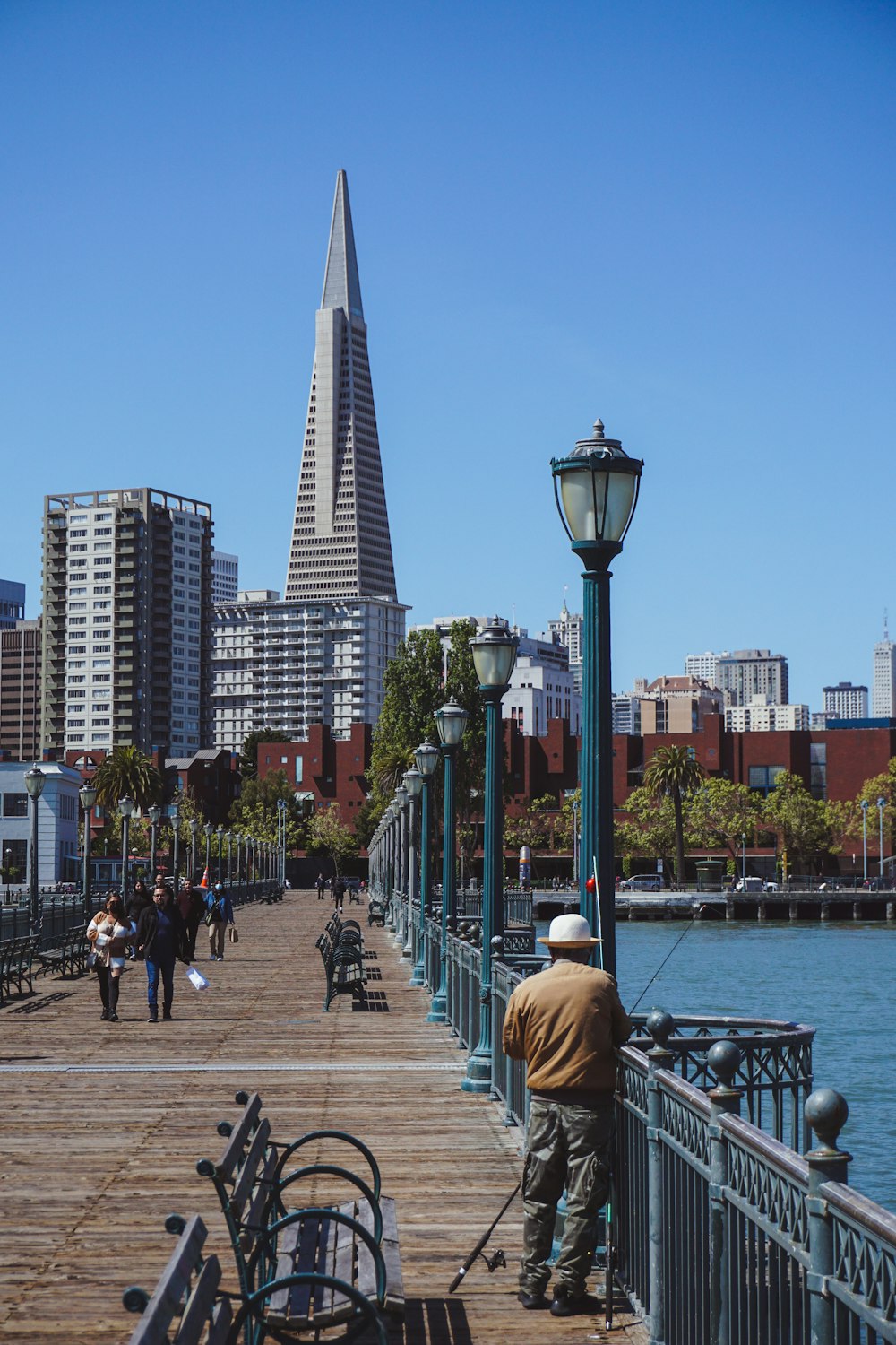 a group of people walking on a boardwalk by a body of water