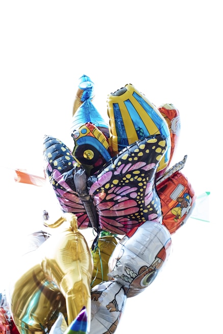 A collection of colorful foil balloons with various designs, including a golden horse, a butterfly with intricate patterns, cartoon characters, and other playful decorations.