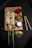 A wooden board holds two skewers of cooked chicken kabobs garnished with herbs. Accompanying the skewers are three small bowls containing sauces: a red sauce, a green chutney with chili flakes, and a white yogurt-based dip. Freshly cut lime, slices of green pepper, shredded cabbage, and other greens are scattered around the board, adding a fresh touch.