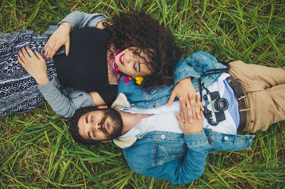 a man and woman lying in the grass with cameras