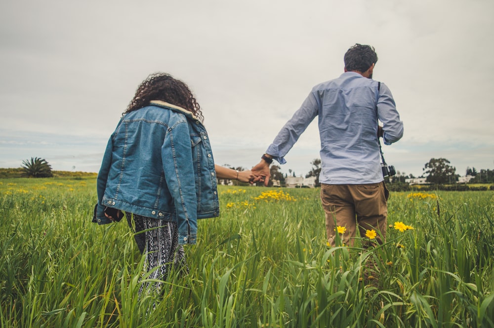 um homem e uma mulher de mãos dadas em um campo de grama