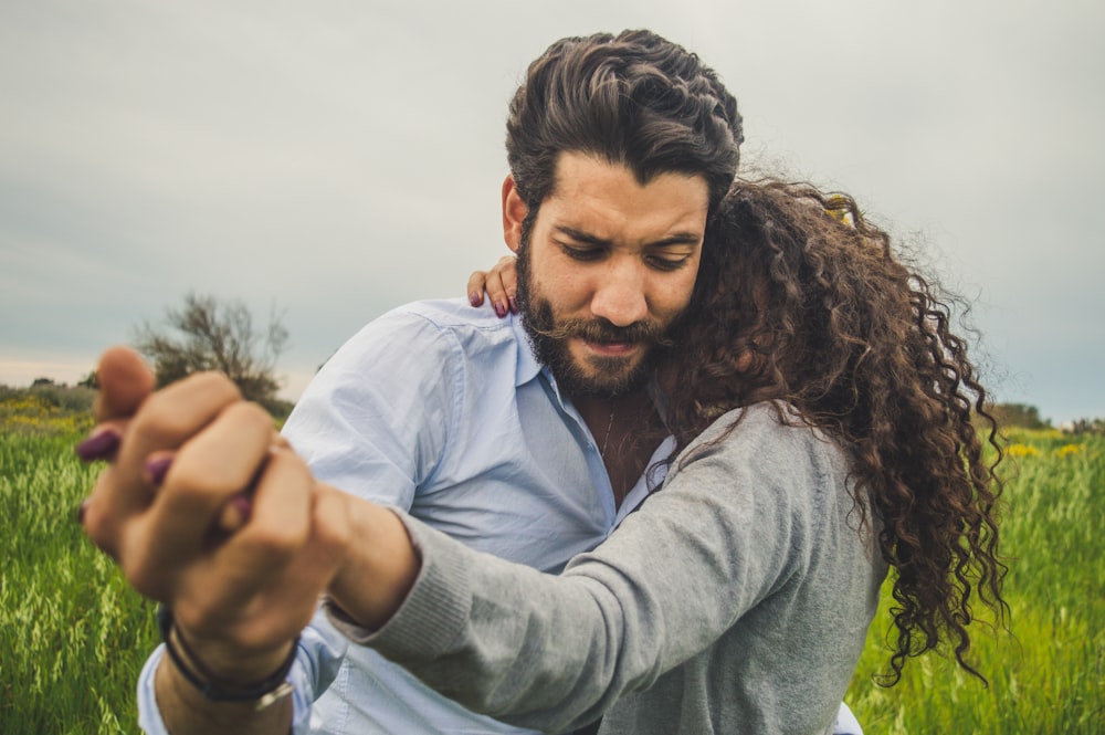 a man with long hair holding a woman's hand