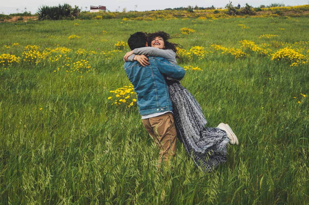 a man and woman hugging in a field of grass