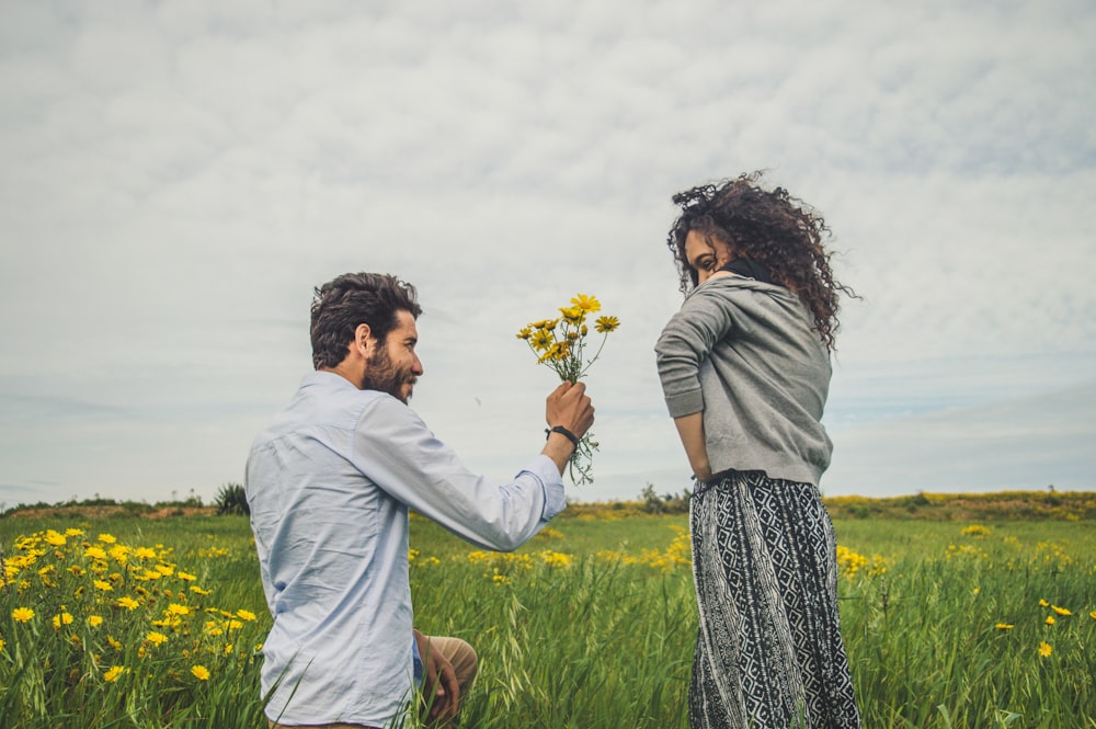 a man and woman holding hands and looking at a flower