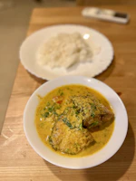 Close-up of a vibrant Bengali fish curry served in a traditional brass bowl.