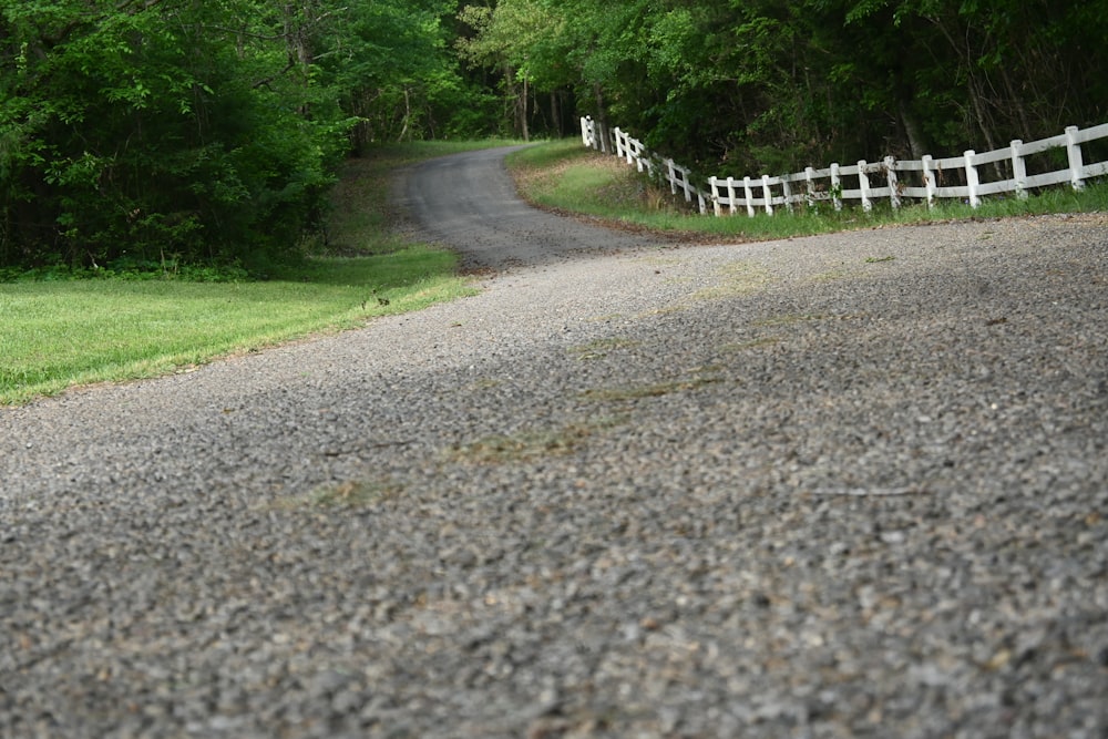a gravel road with white fences