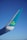 An airplane wing with a blue and white design featuring a green shamrock on the winglet against a clear blue sky.