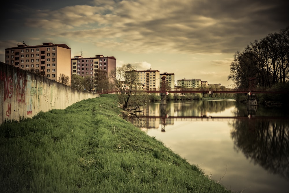 a river with grass and buildings along it