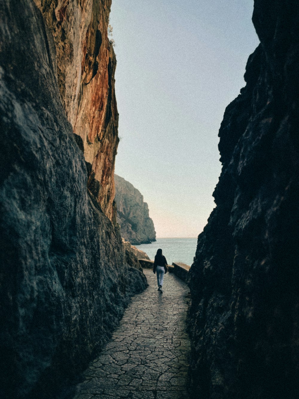 a person walking on a stone path between large rocks