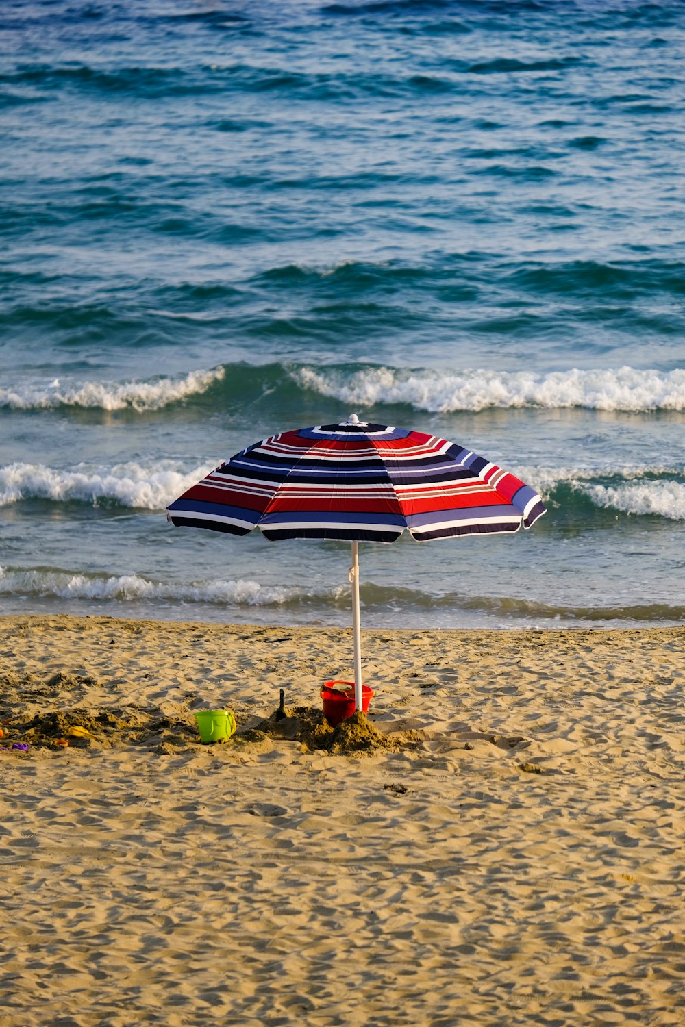 a beach with a beach umbrella and buckets
