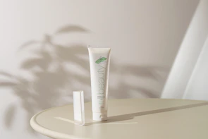 Minimalist cream jar on a marble surface with delicate shadows