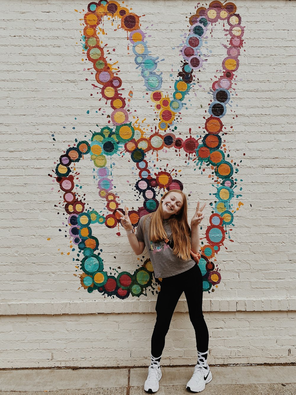 a person posing in front of a wall with art