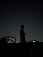 Wide shot of a lone figure silhouetted against a dark urban skyline.