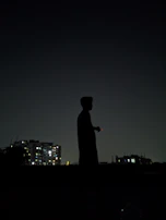 A silhouette of a protester holding a candle against a dark cityscape at night.