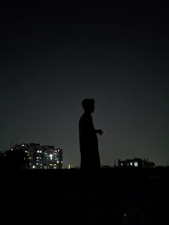 Silhouette of a man standing tall against a dark cityscape, embodying silent authority and independence.