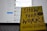 A book titled 'Show Your Work!' by Austin Kleon is propped open in front of a laptop displaying a blurred social media interface. The book cover is bright yellow with bold, dark blue text.