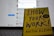 A book titled 'Show Your Work!' by Austin Kleon is propped open in front of a laptop displaying a blurred social media interface. The book cover is bright yellow with bold, dark blue text.