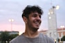 a man smiling with a tower in the background