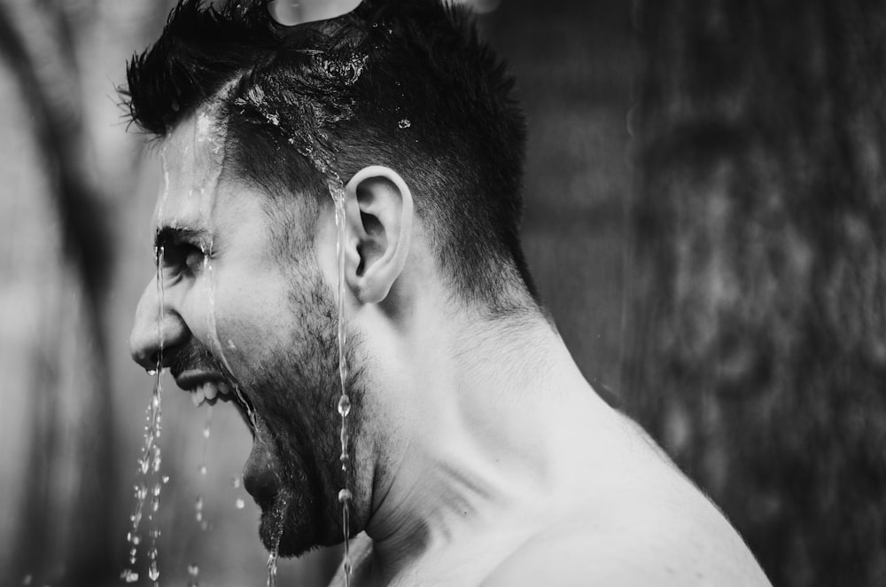 a man drinking water from a faucet