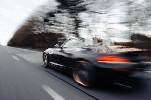 A dynamic shot of a convertible speeding along a coastal highway