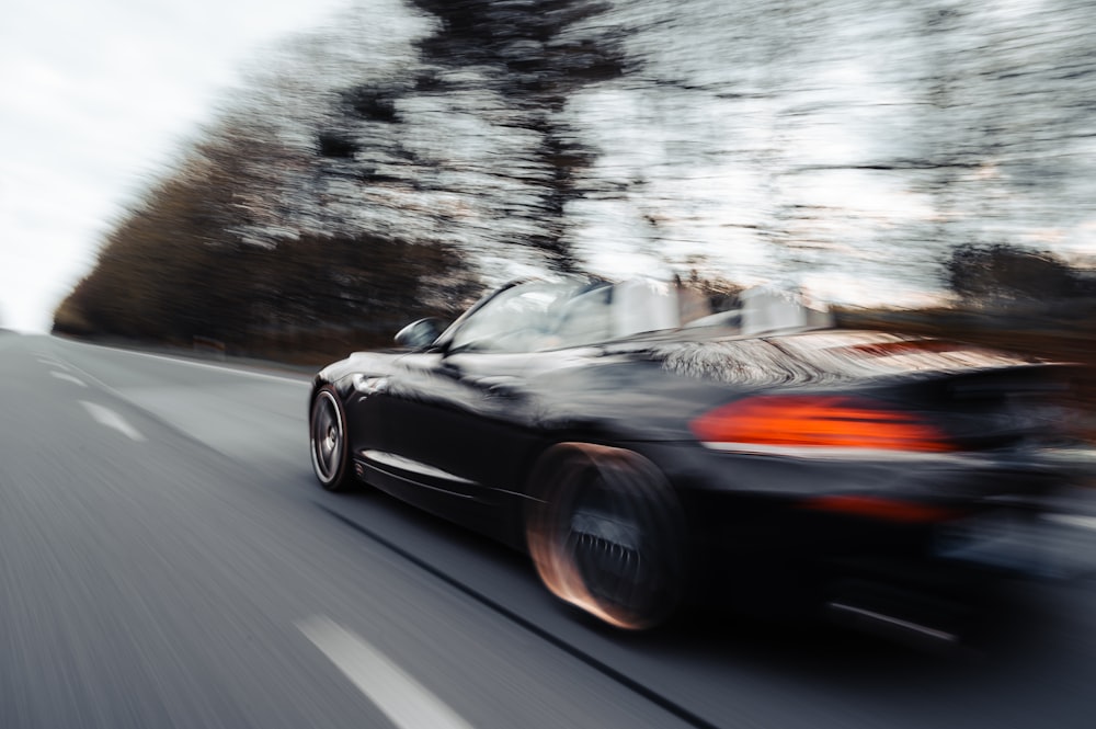 a black sports car driving on a road