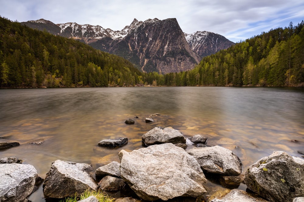 a lake with rocks and mountains in the background