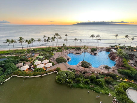 Elegant beachfront resort with palm trees and golden sunset.