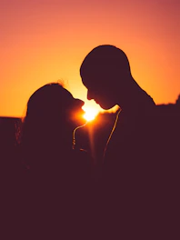 a couple kissing in front of a sunset