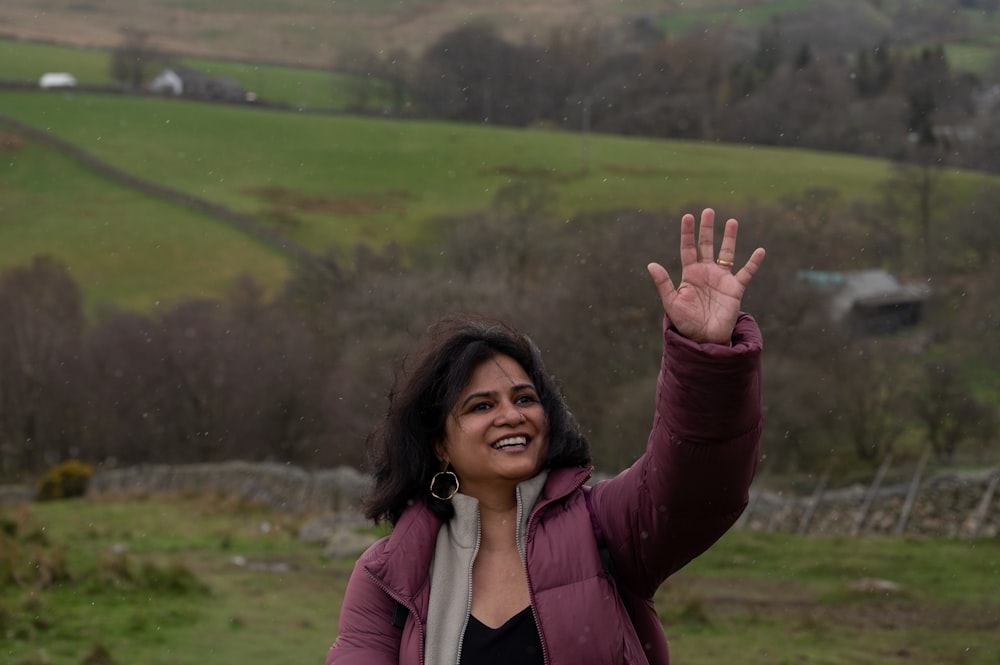 a woman smiling with her hand up