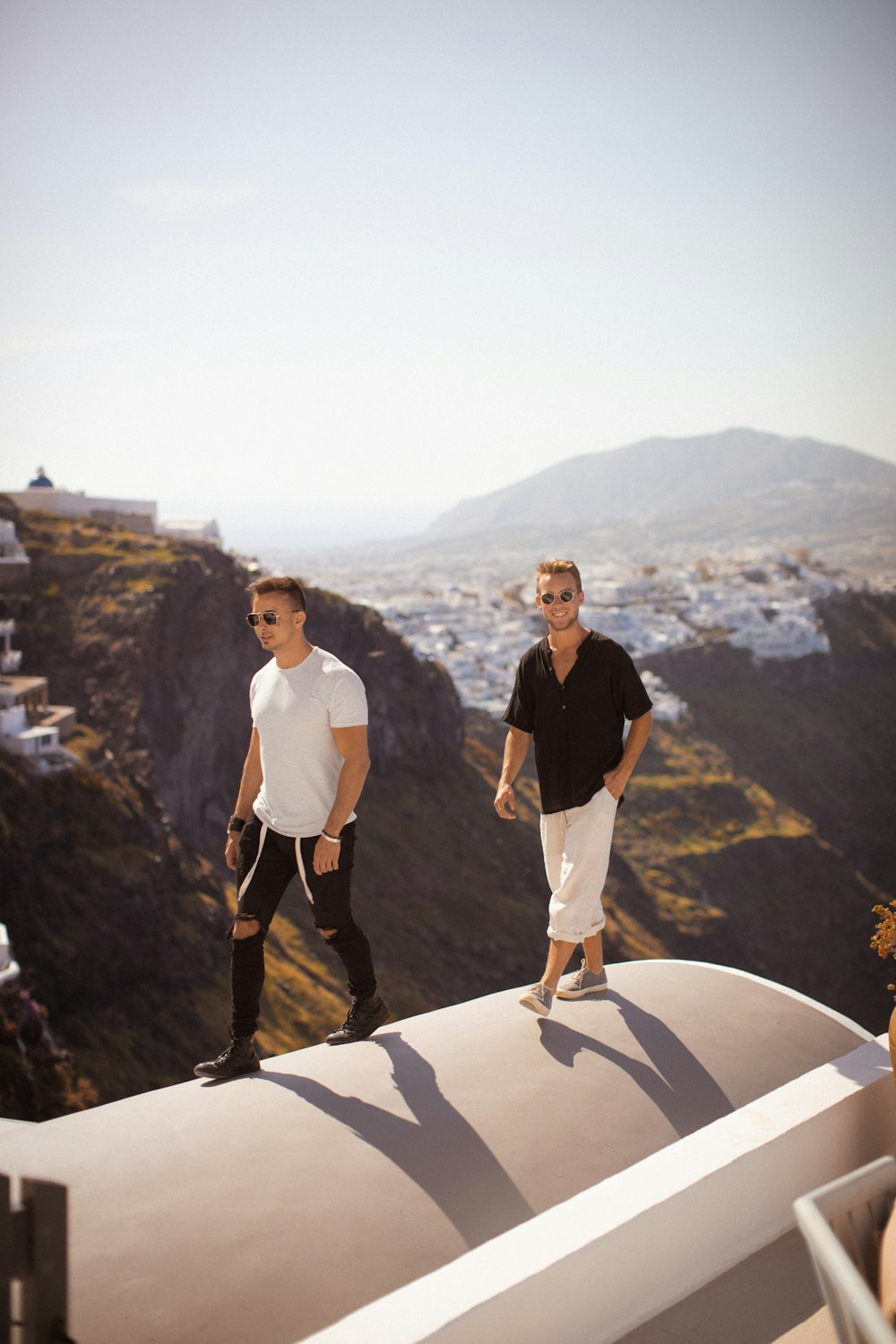 a man and woman standing on a ledge overlooking a city