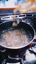 A warm kitchen scene showing a hand pouring boiling water into a Zede instant meal pouch.