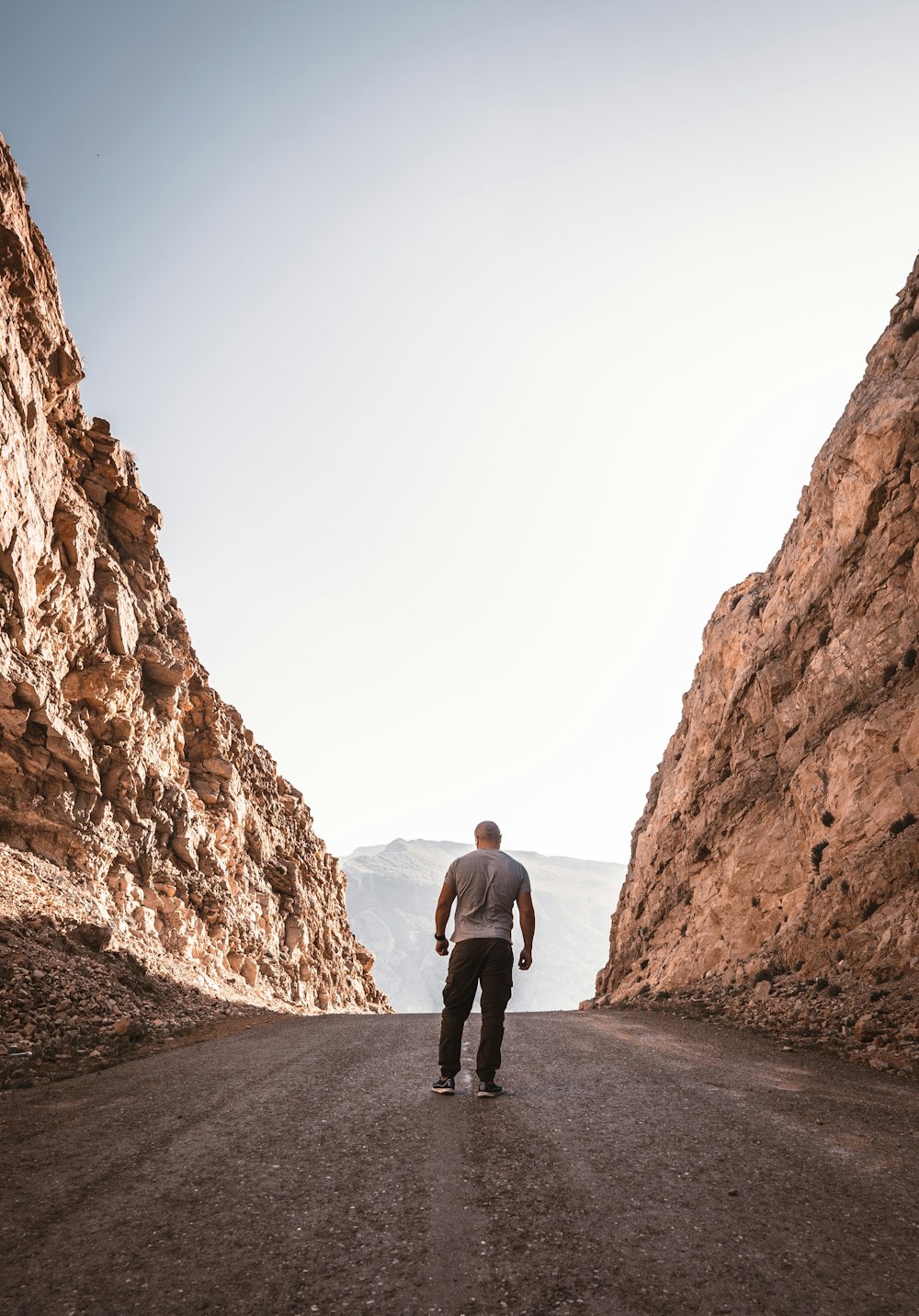 a man standing on a road between large rocks