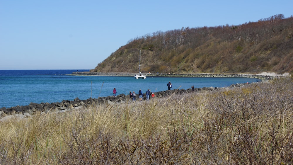 a group of people standing on a rocky shore by a body of water