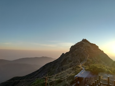 A calm mentor guiding a person through a rugged mountain trail at sunrise.