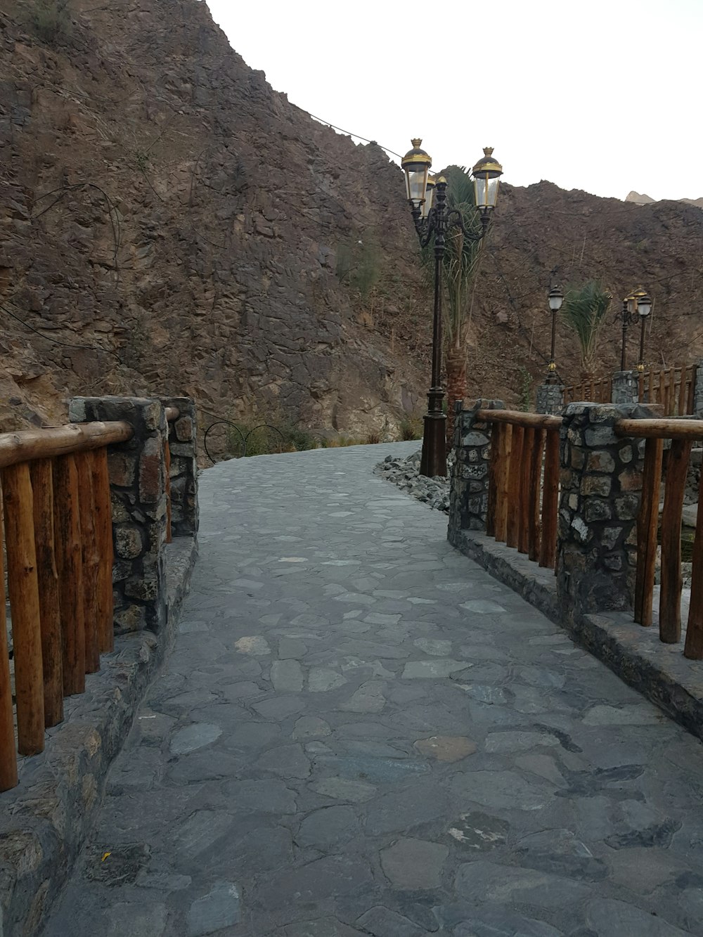 a stone path with a fence and a stone wall with a stone wall