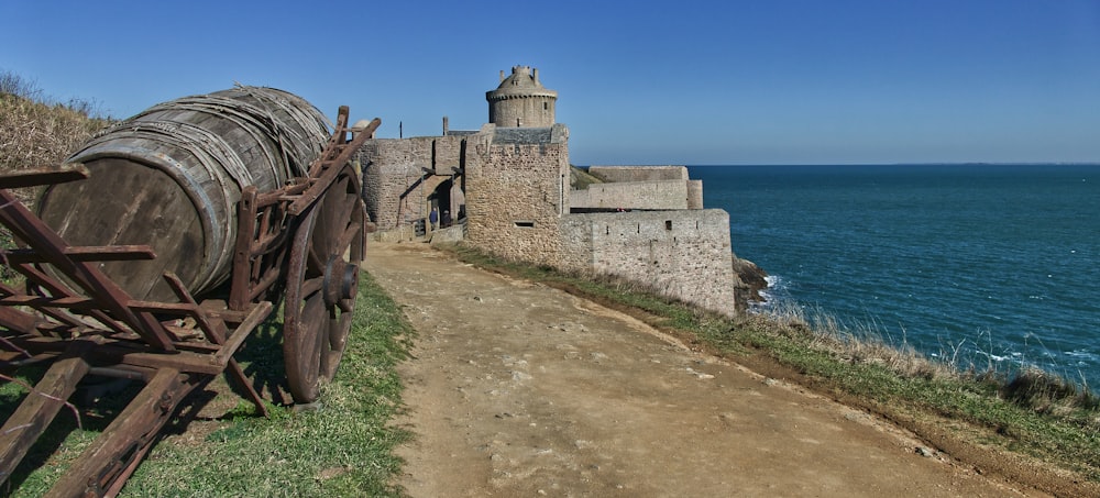 a cannon on a path by a building and water