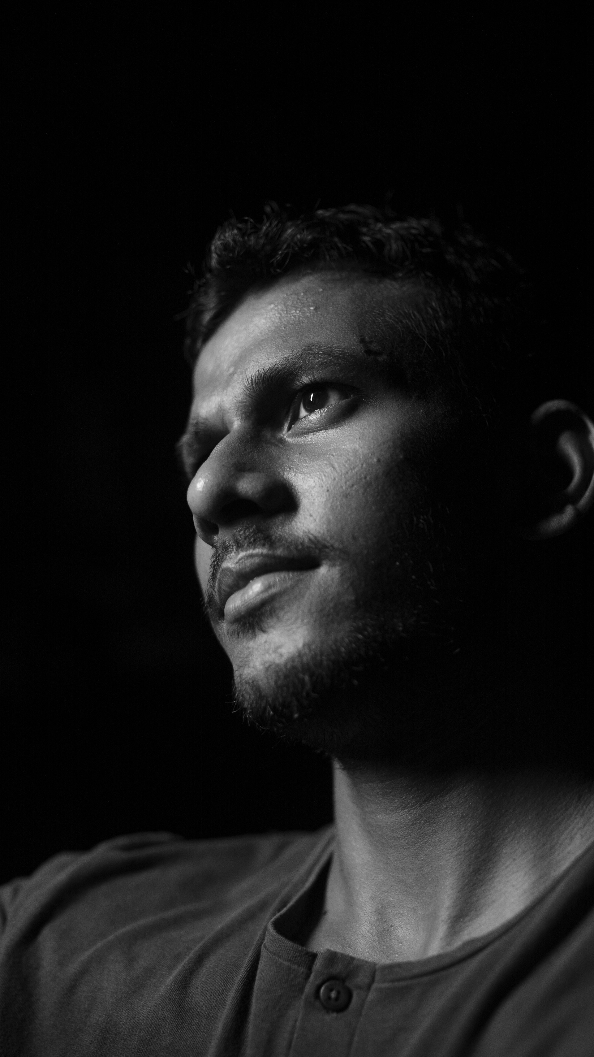 A black and white portrait of a man with a thoughtful gaze, emphasizing texture and contrast in a minimalist style.